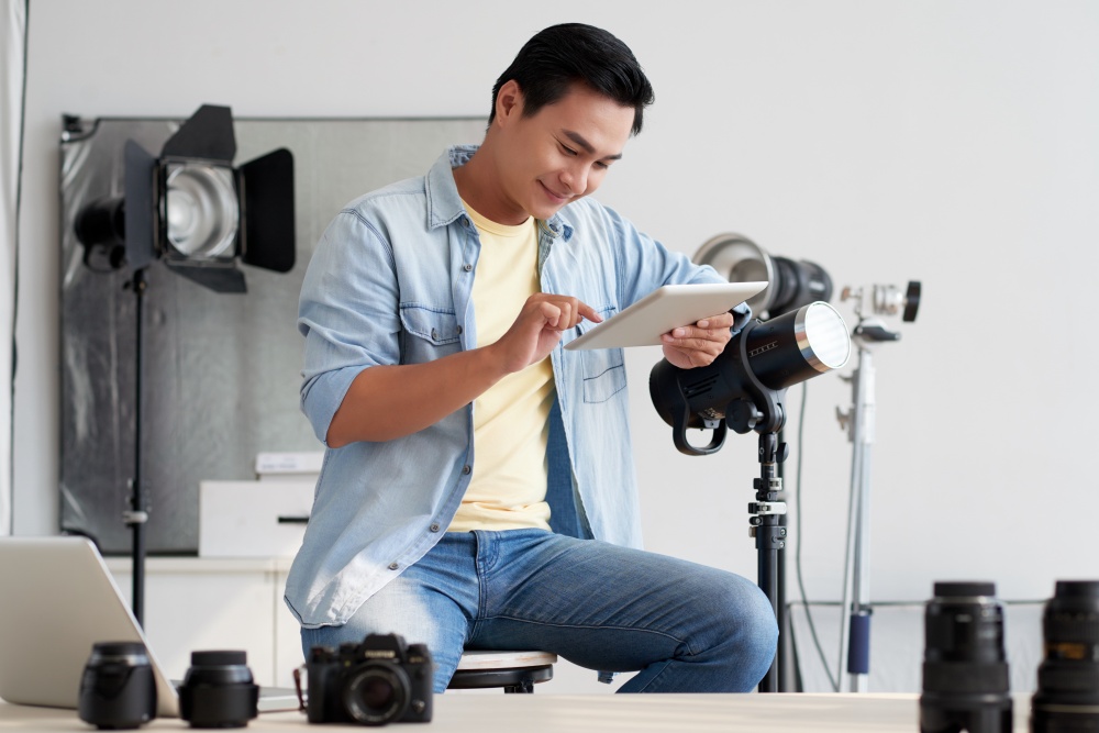 Smiling young Asian man using application on digital tablet